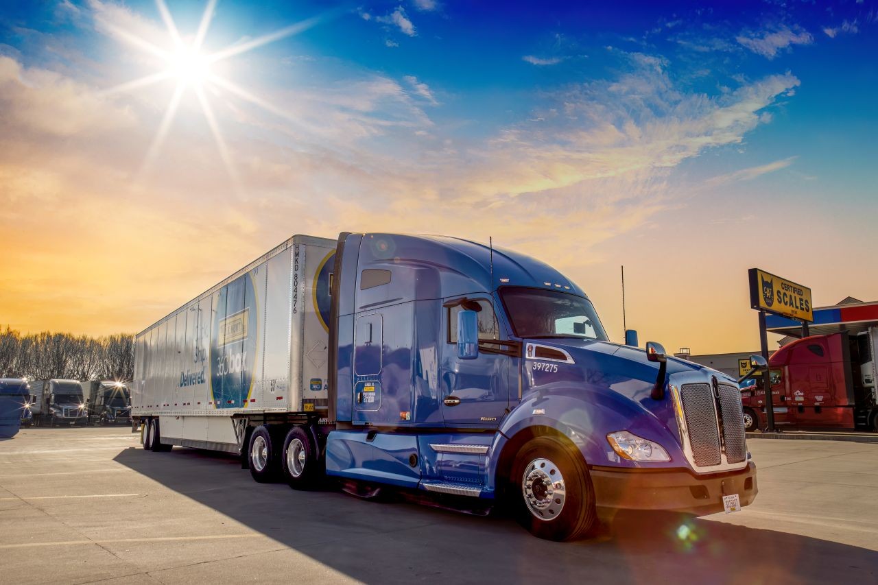 Blue tractor with 360box trailer staged in a truck stop parking lot