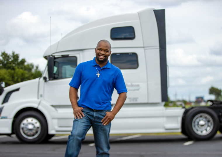 Owner Operator posing for a picture in front of his truck